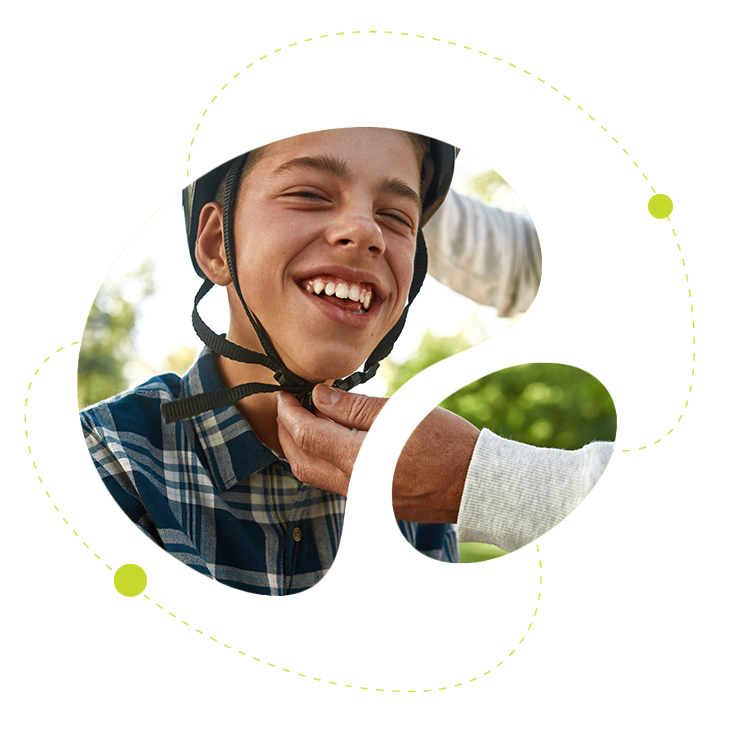 Pojke med hjälm som får hjälp att spänna fast den – glädje och trygghet inför aktivitet.